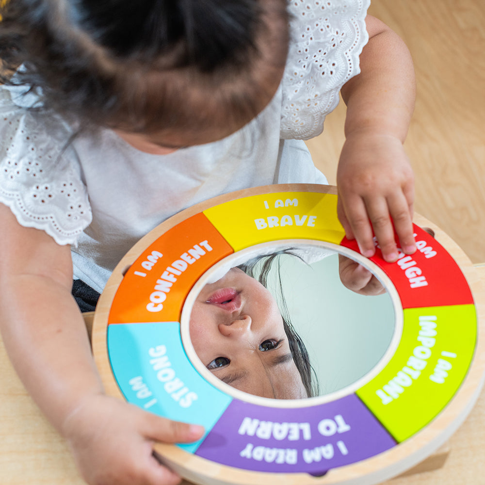 Child interacting with a colorful wheel toy on a wooden floor