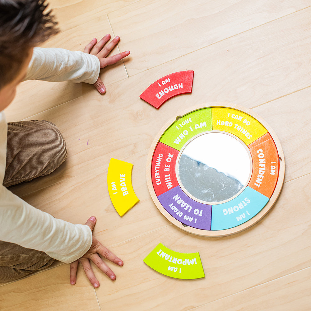Child playing with a colorful wheel of emotions on a wooden floor