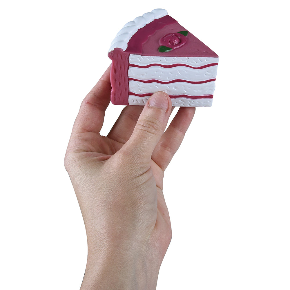 Hand holding a small toy cake with pink filling on a white background