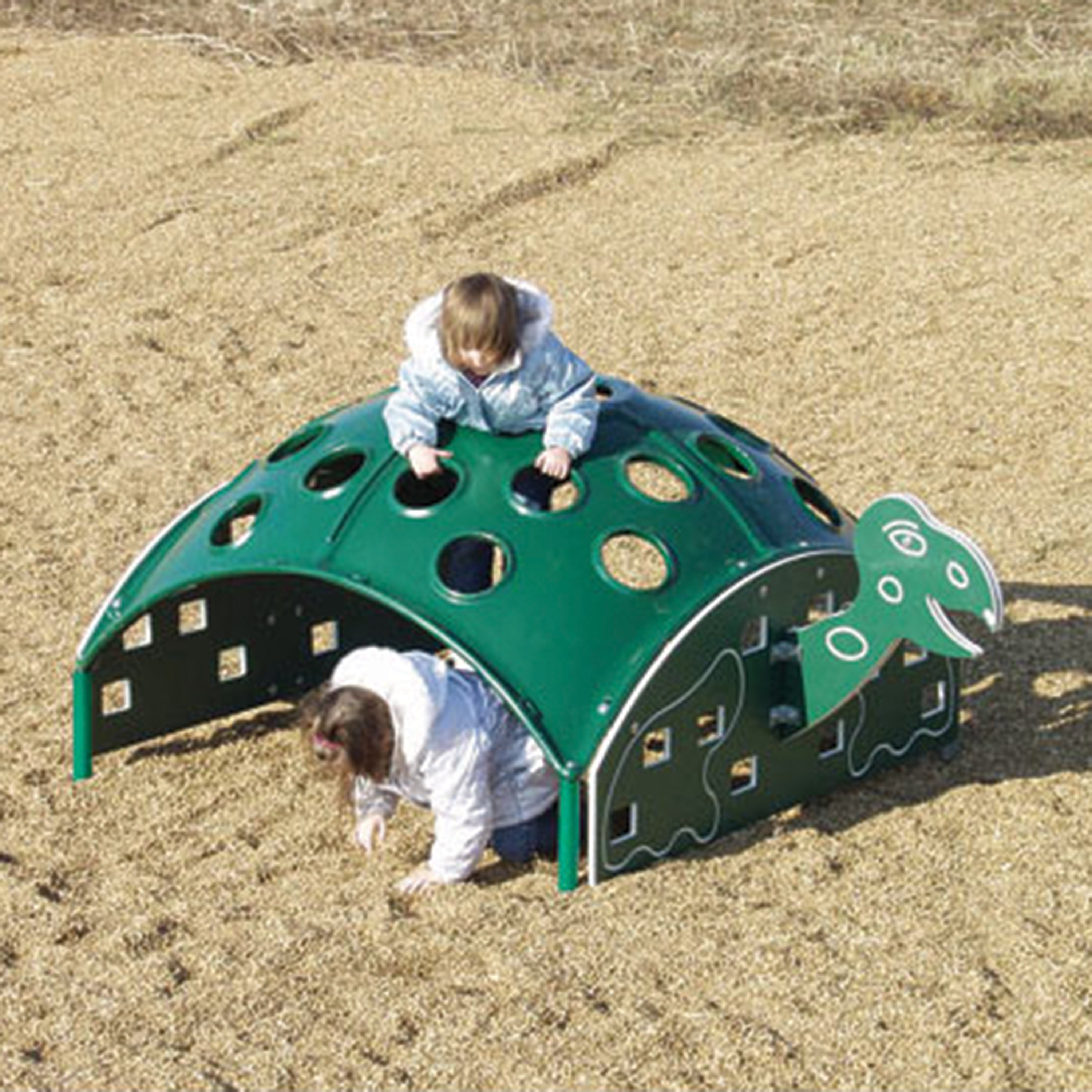 Children playing on a green playground structure shaped like a turtle in an open field.