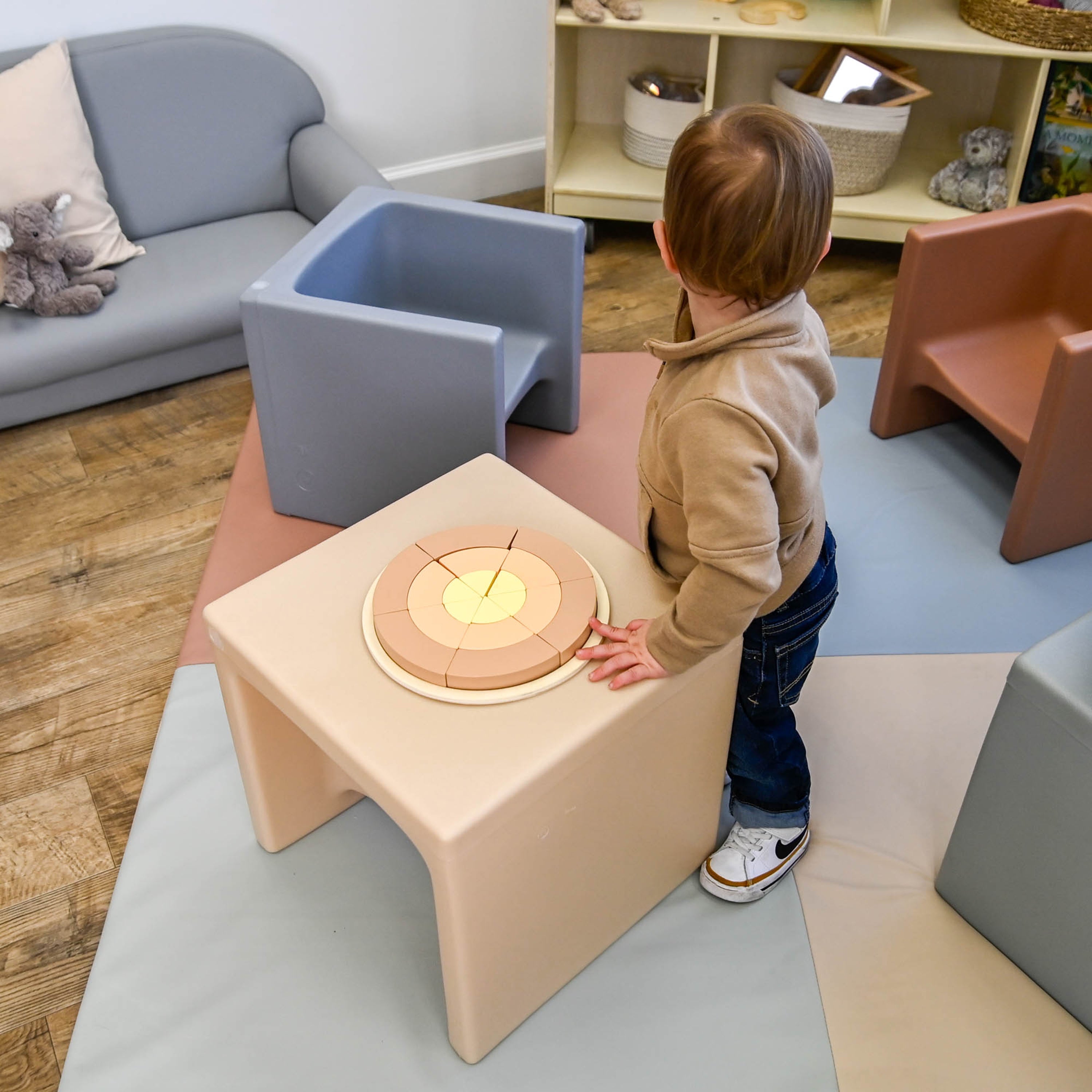 Child playing with a toy on a colorful playroom floor.
