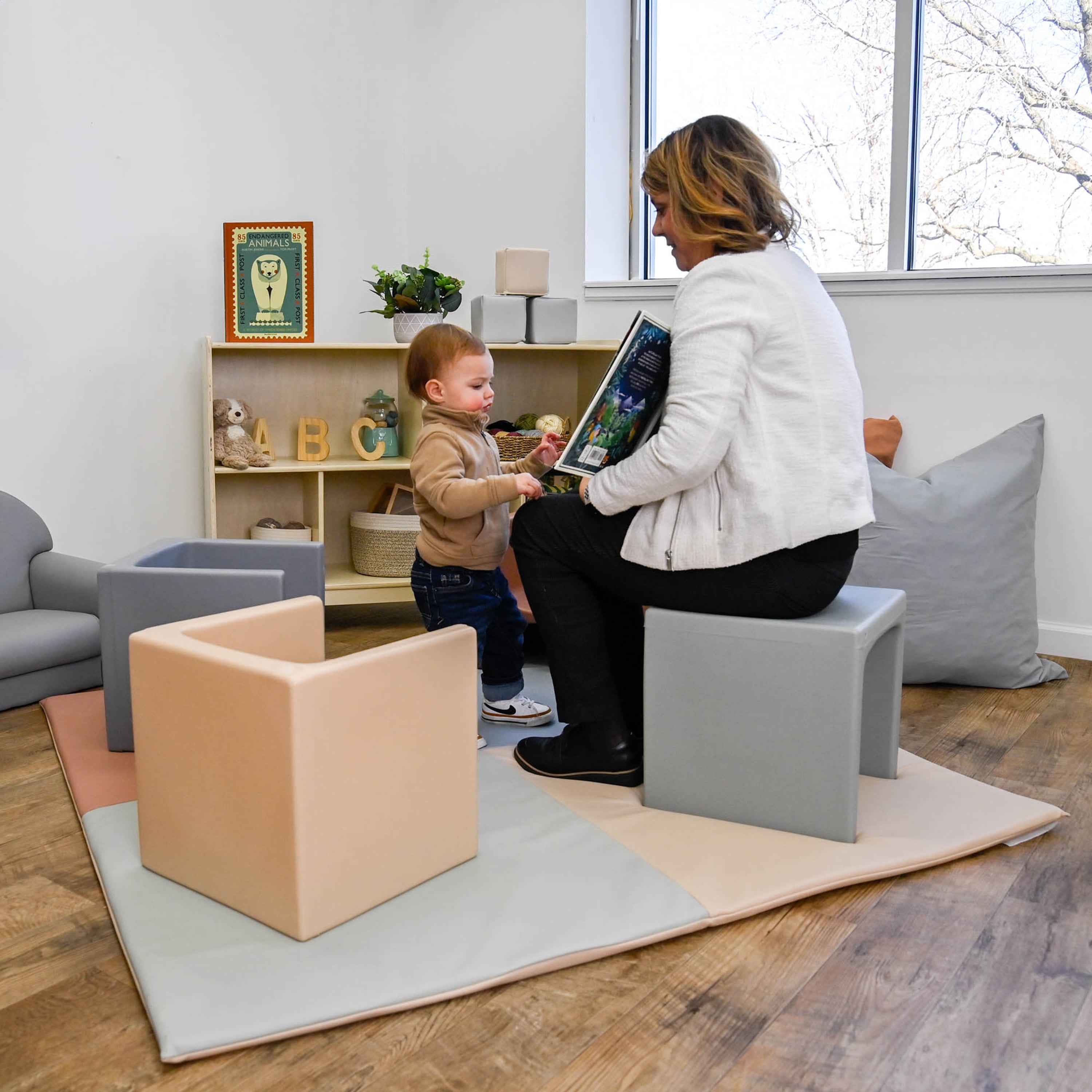 Woman and child in a modern living room with soft furniture and decor.
