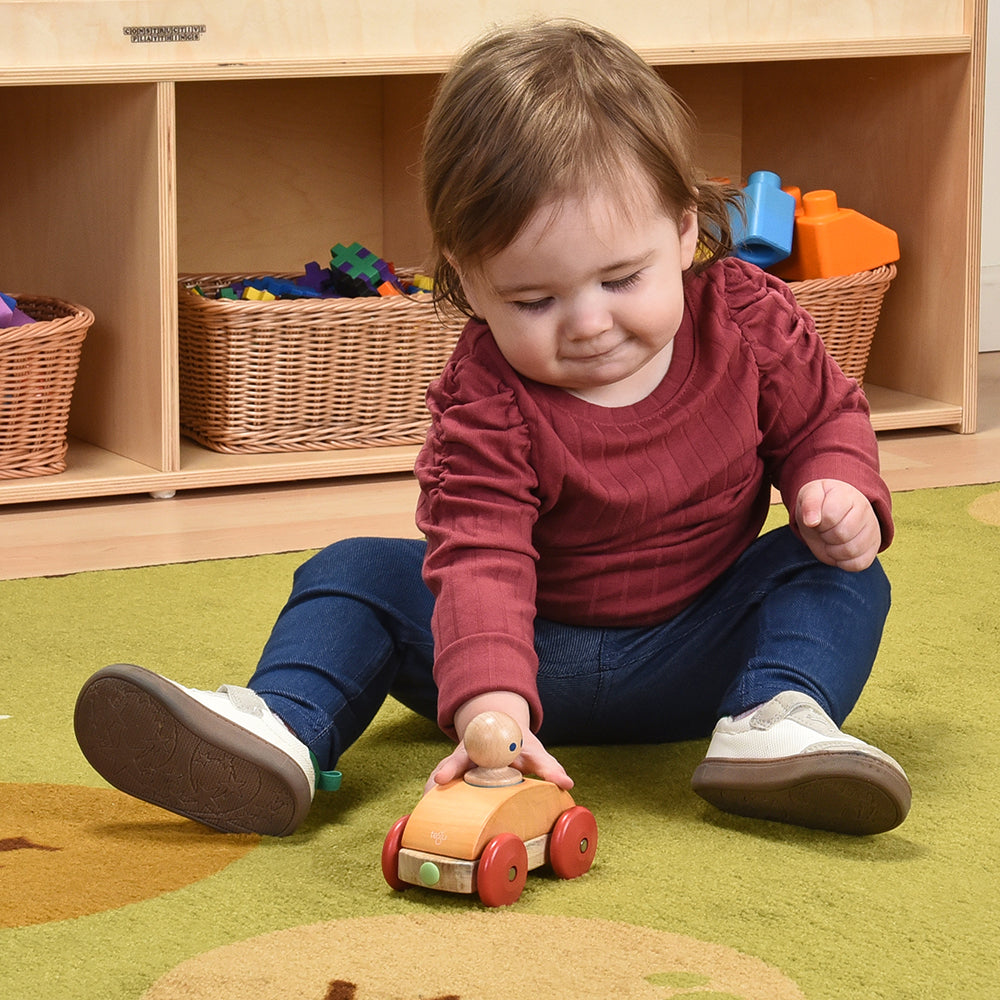 Toddler Interacting with Tegu Orange Magnetic Racer in the classroom