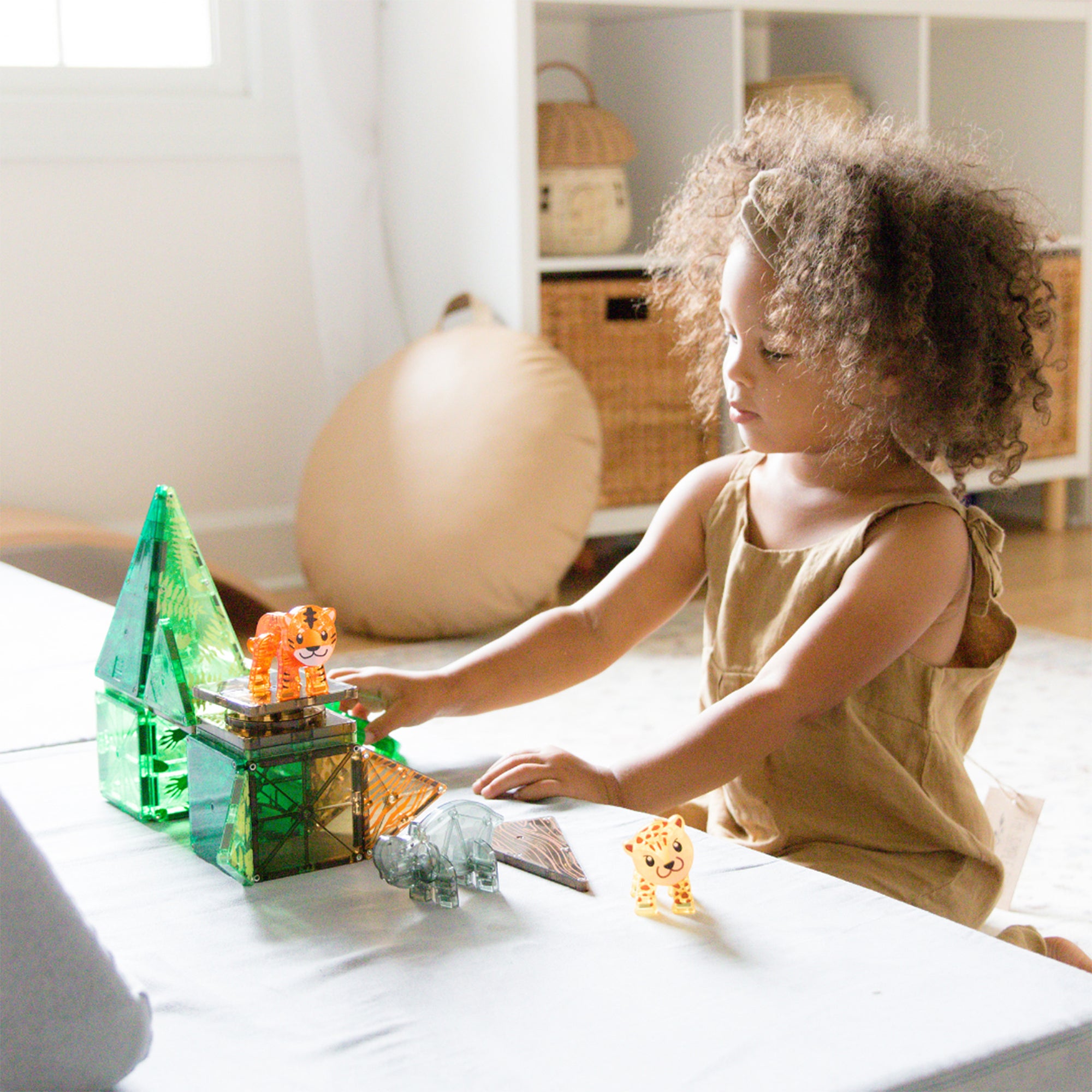 Child playing with toy figures on a bed in a bright room
