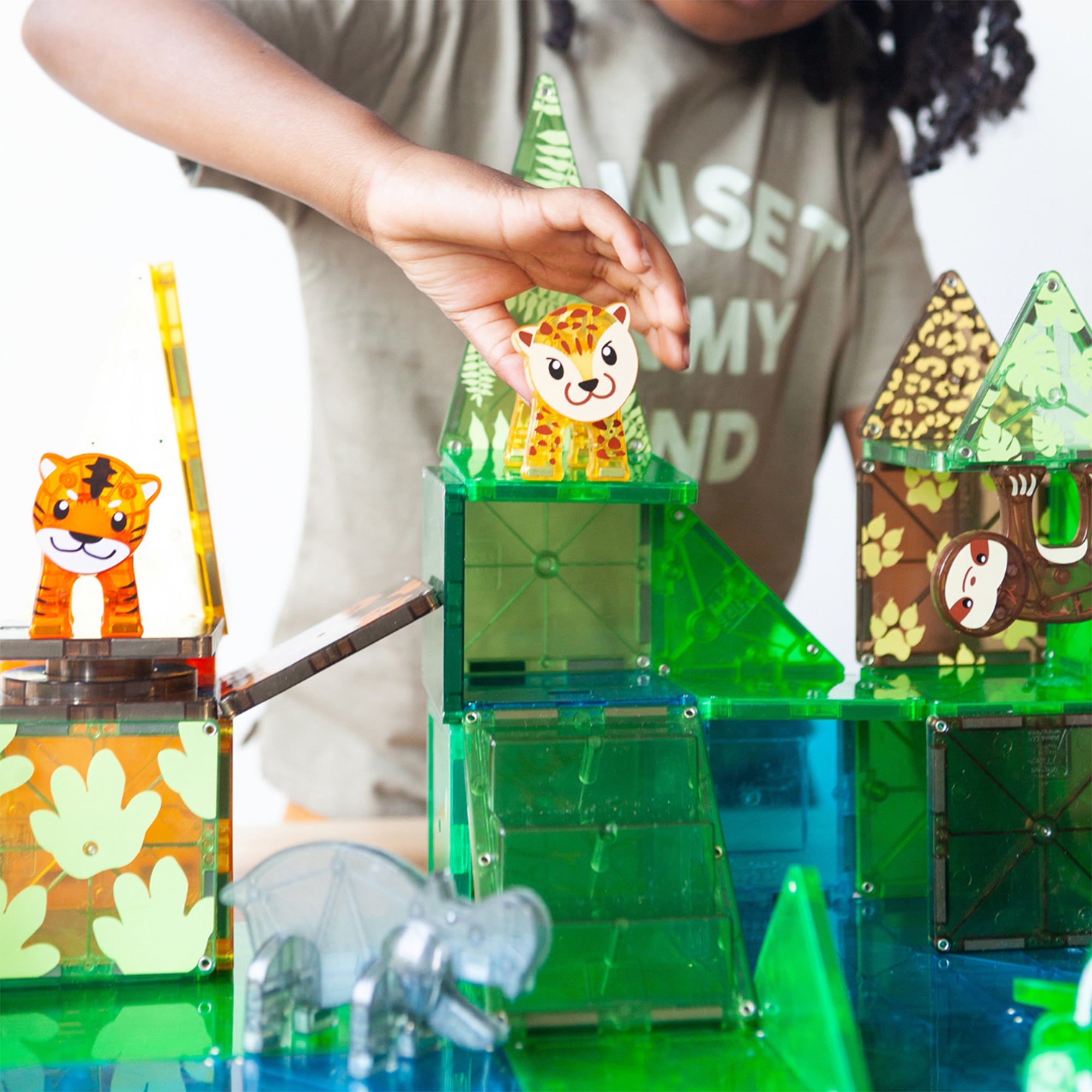 Child playing with a green building block set, surrounded by other colorful blocks.