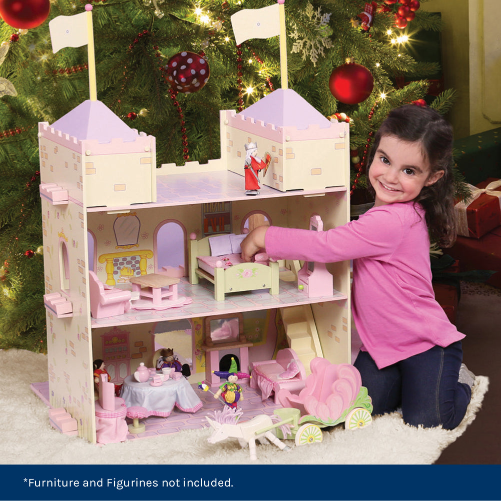 Child playing with a dollhouse in front of a decorated Christmas tree.