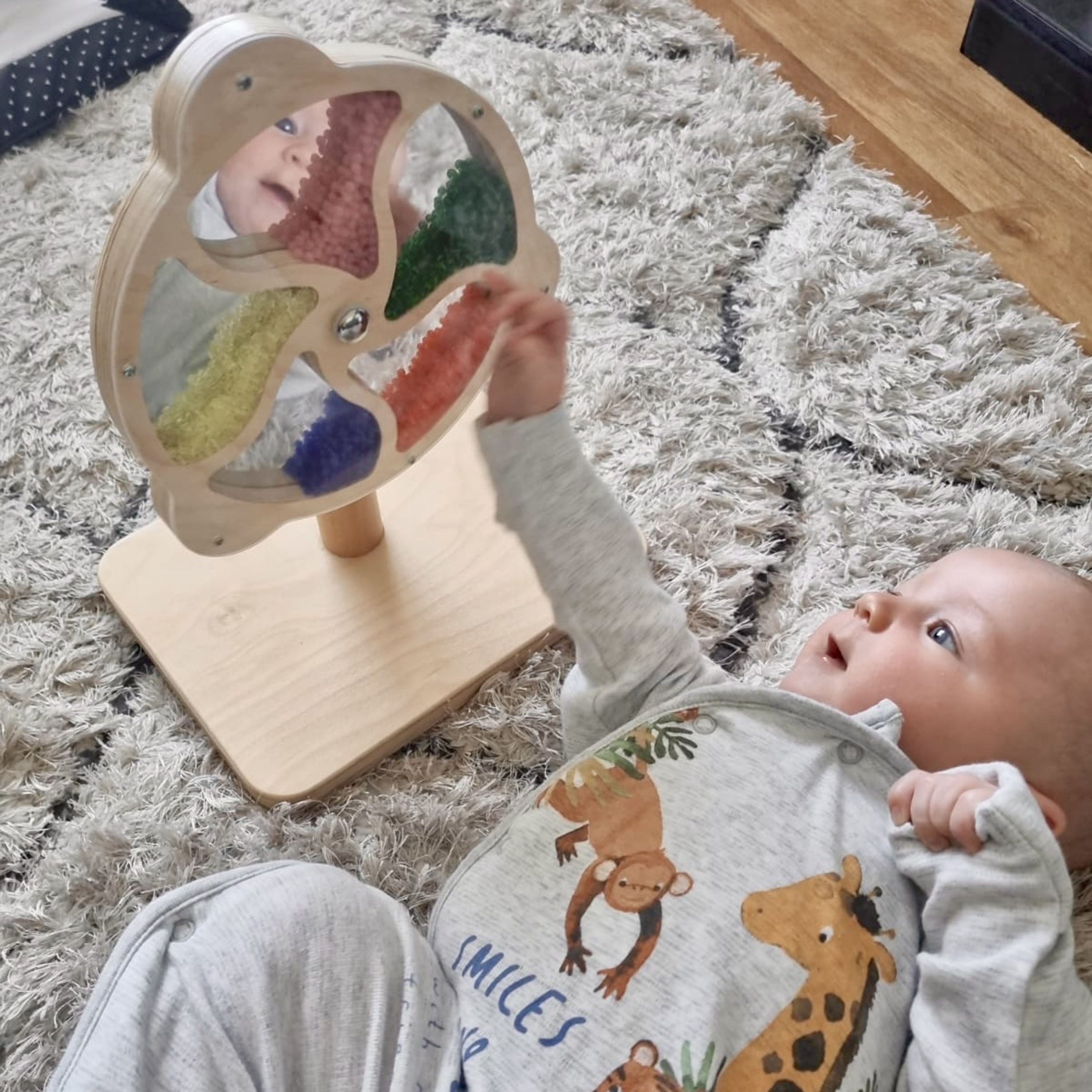 Baby interacting with a colorful educational toy on a carpeted floor