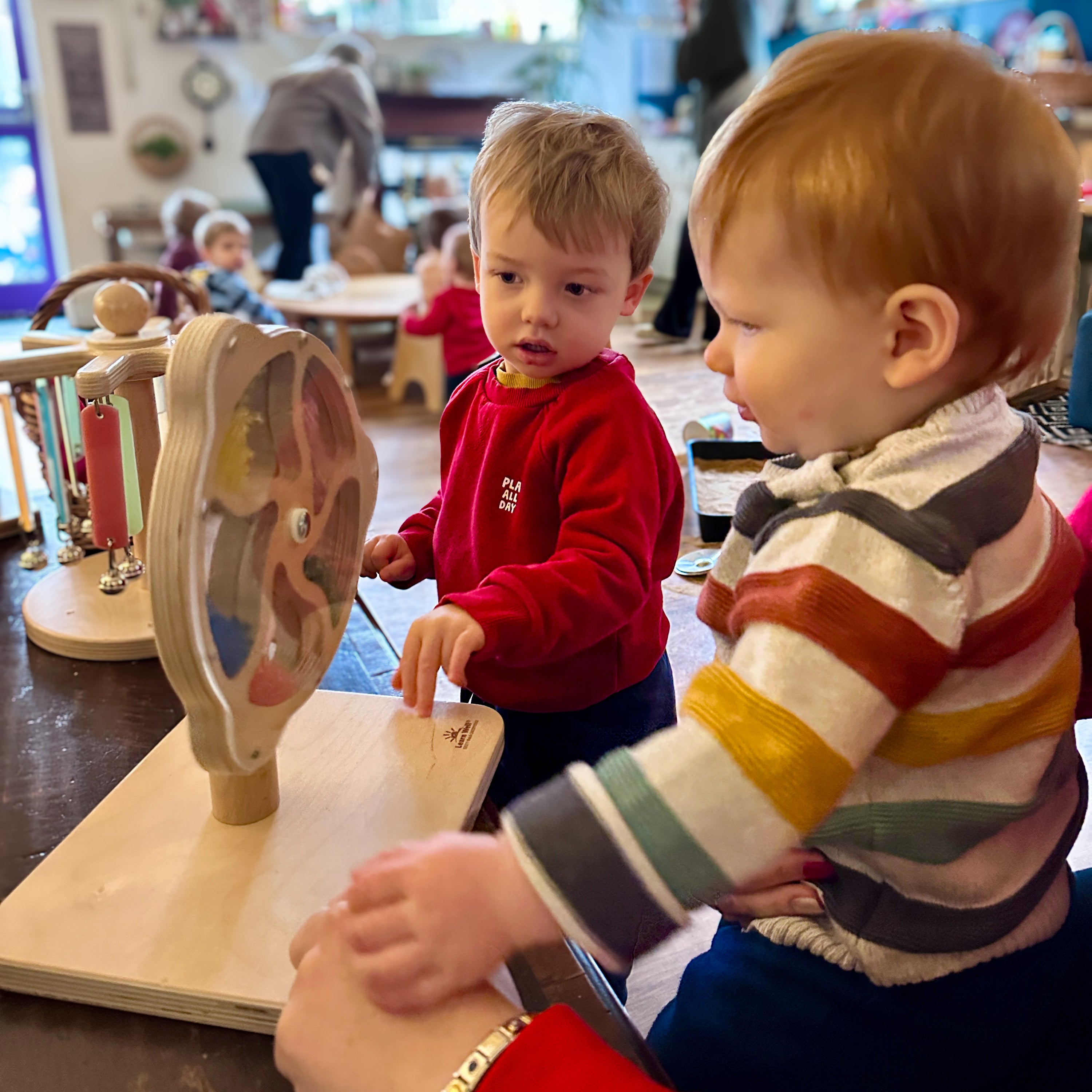 Two children playing with a wooden educational toy in a classroom setting.