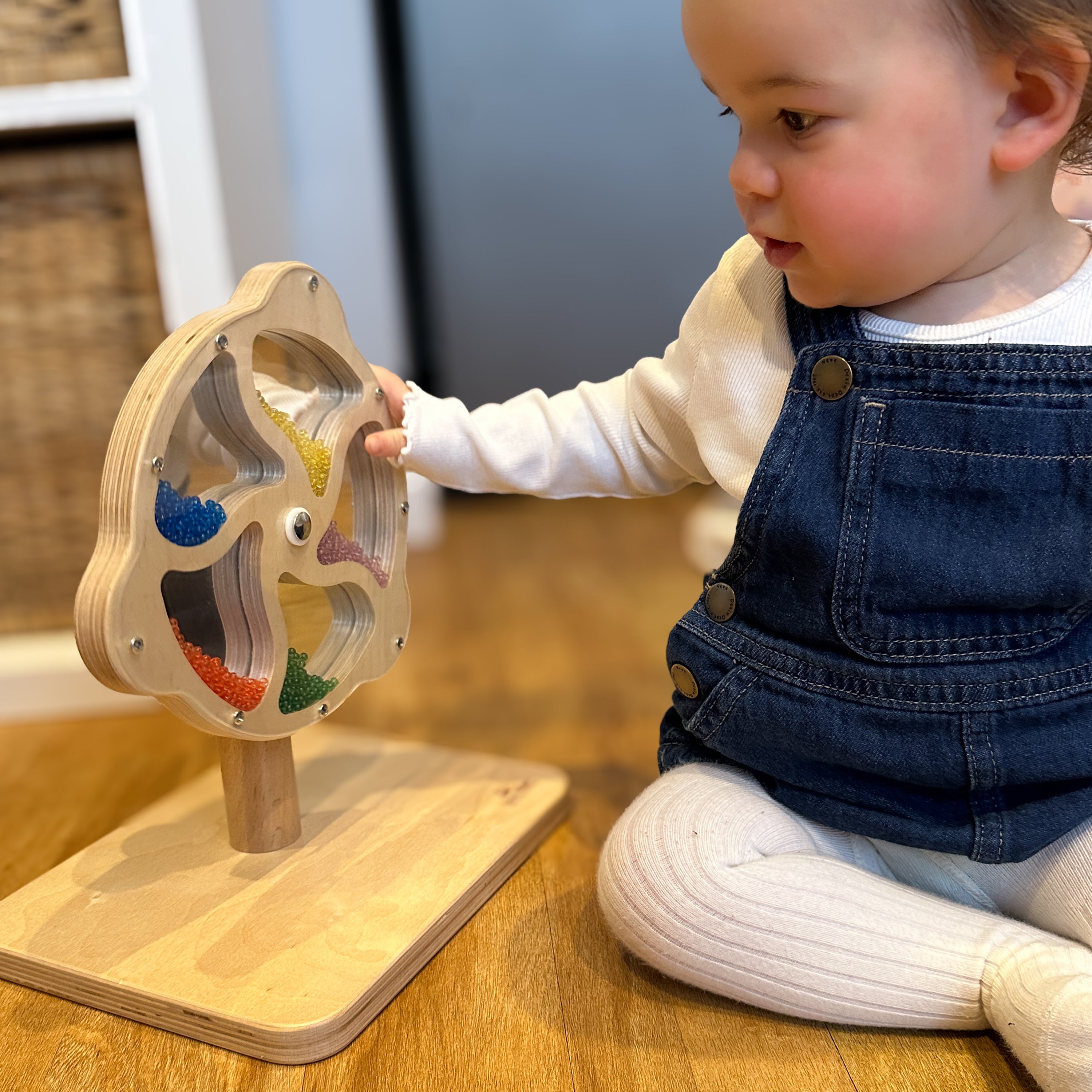 Child playing with a wooden educational toy on a wooden floor.