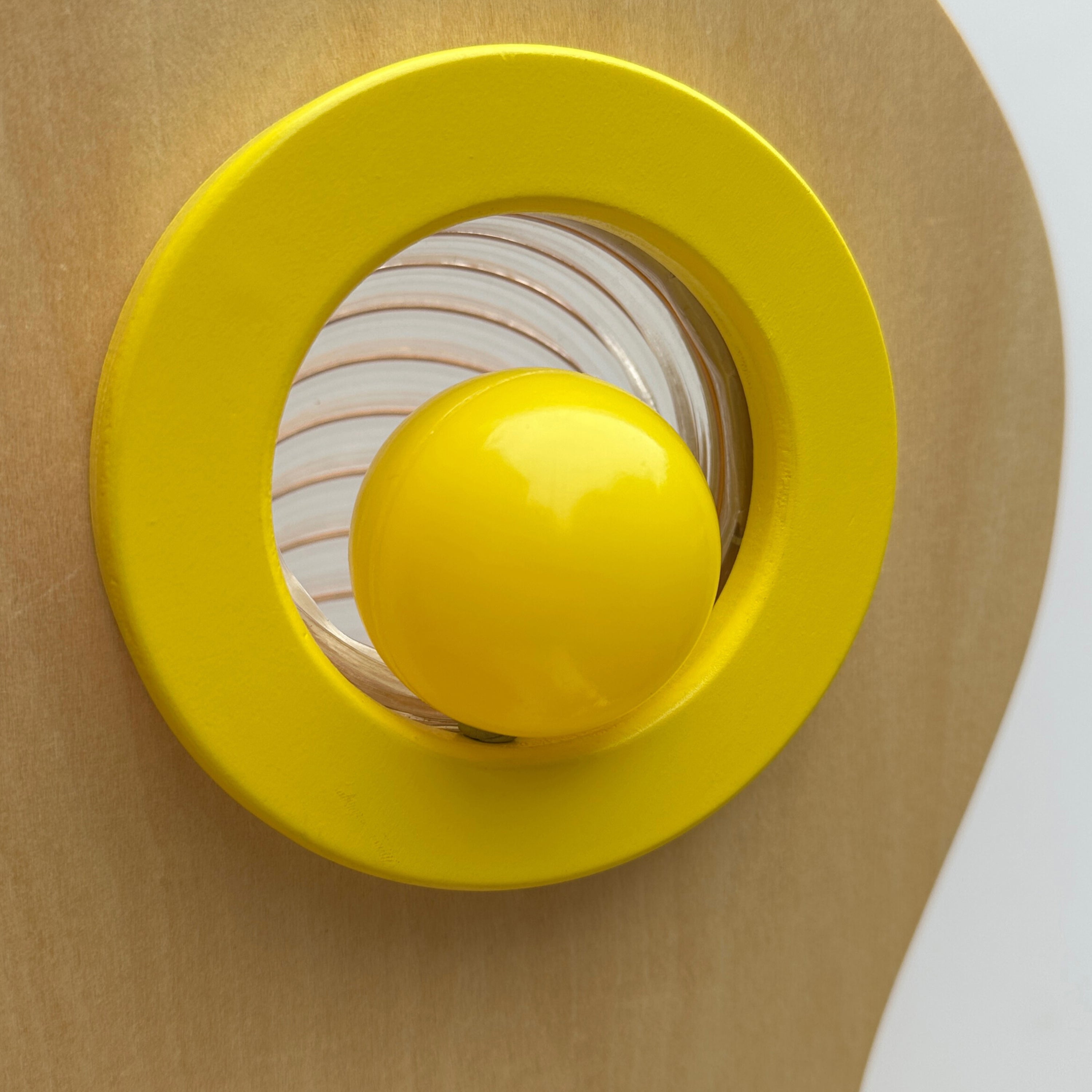 Yellow object with a circular design on a beige background