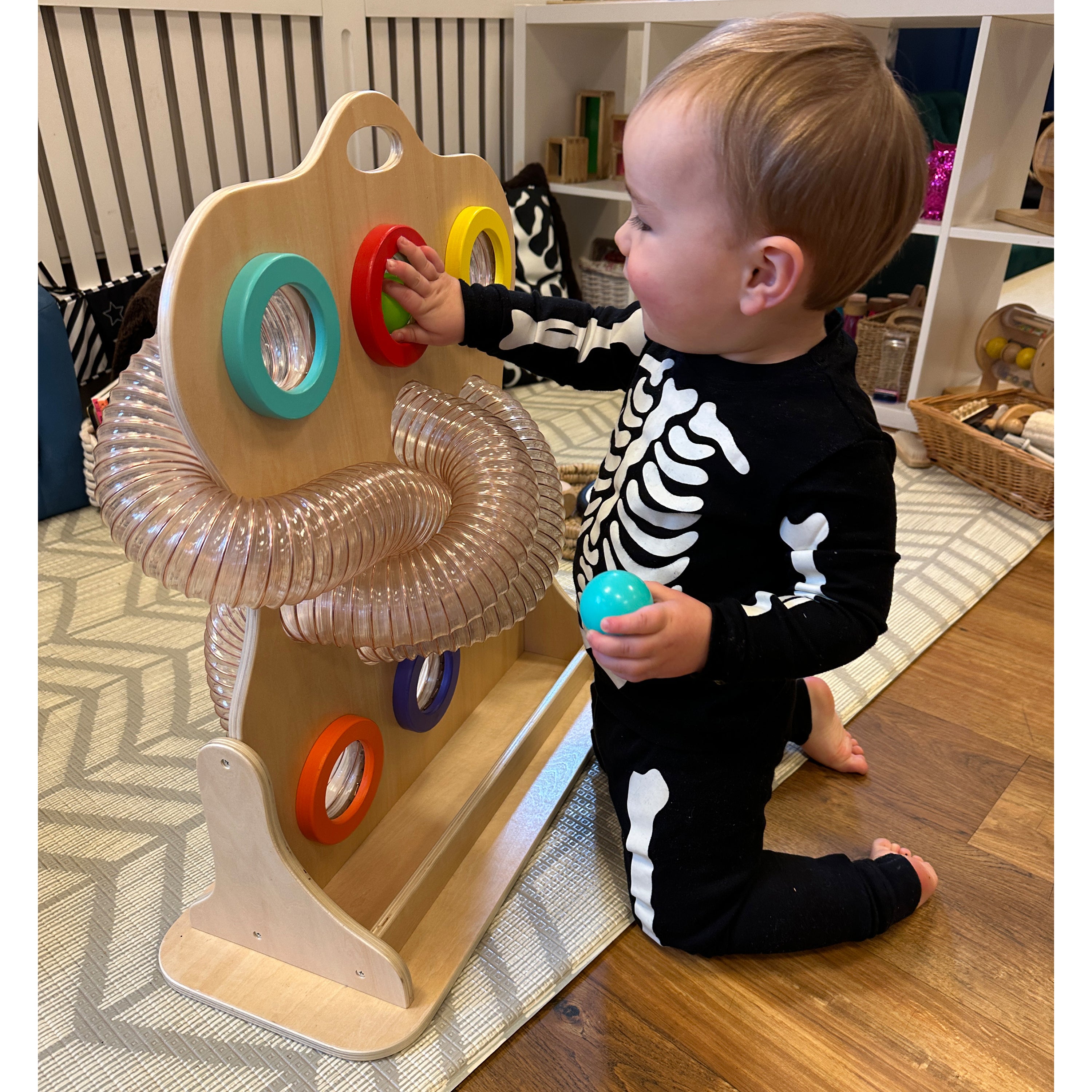 Child playing with a colorful educational toy on a wooden floor.