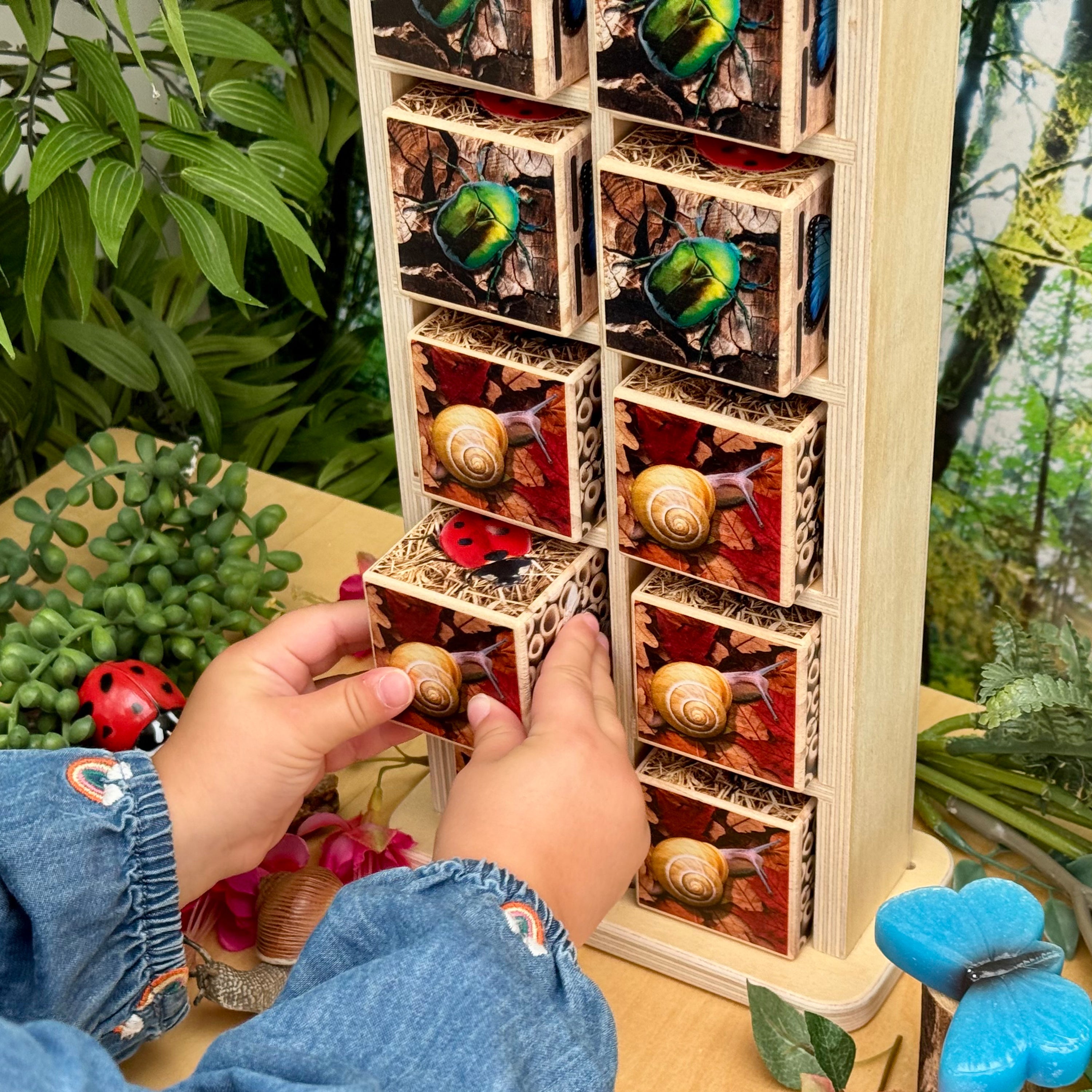 Wooden puzzle with snail and ladybug designs, held by a person with a plant and toy in the background.